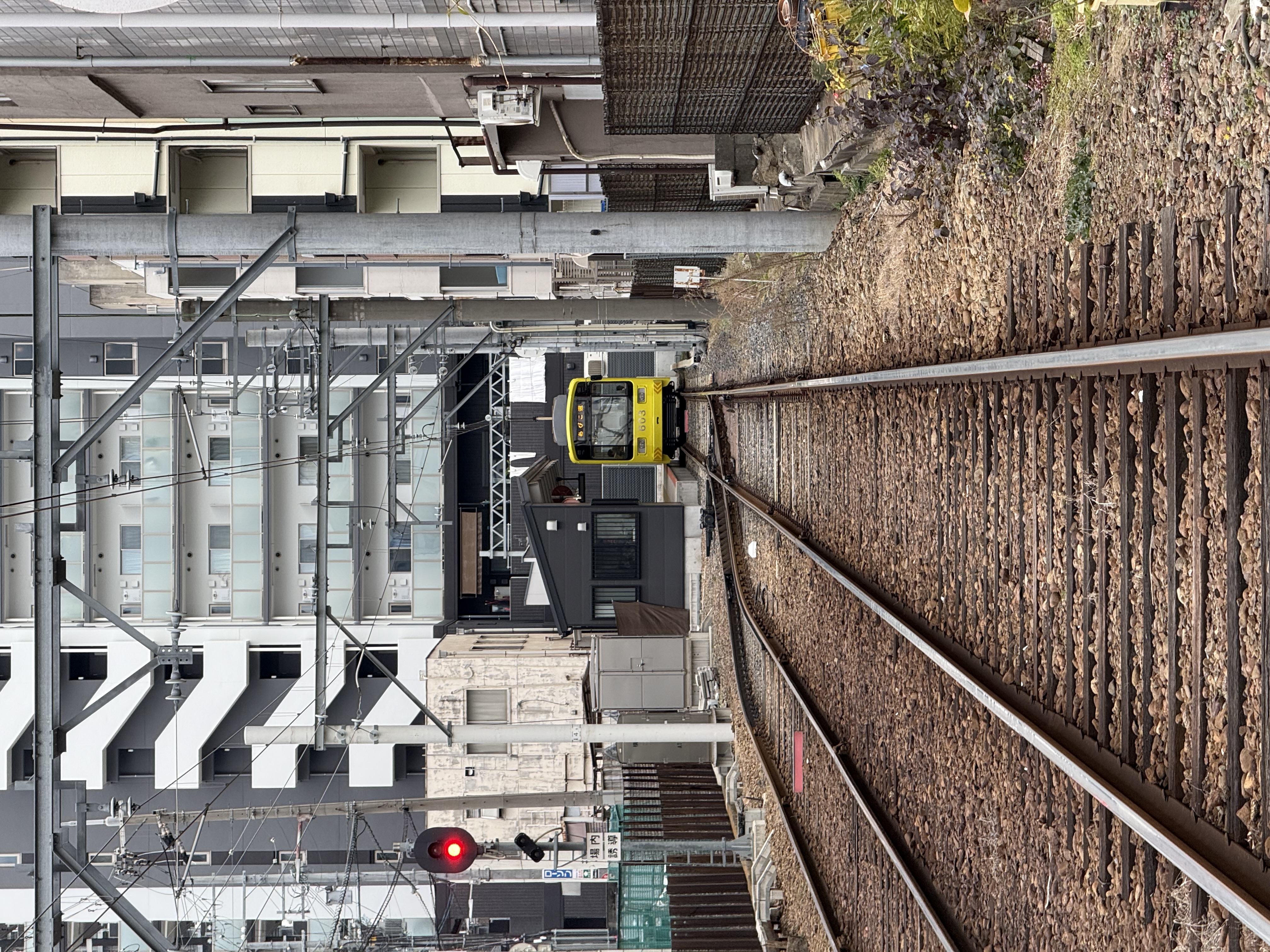 An out-of-service train is nestled between apartment buildings and overhead wires
