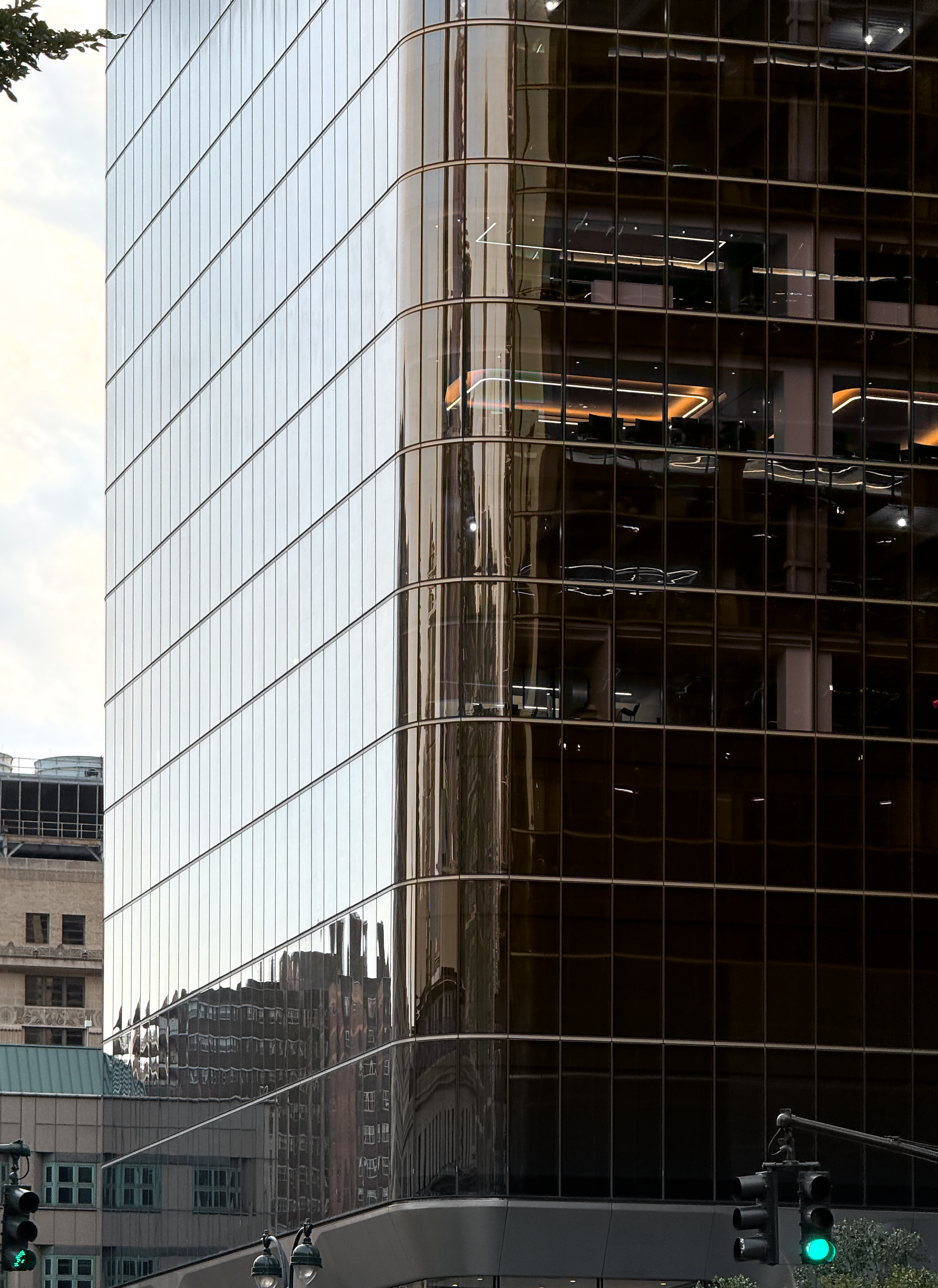 an office building looks normal from the outside, but as soon as the glass rounds the corner & stop reflecting the exterior, you can see the interior glow a deep yellow.