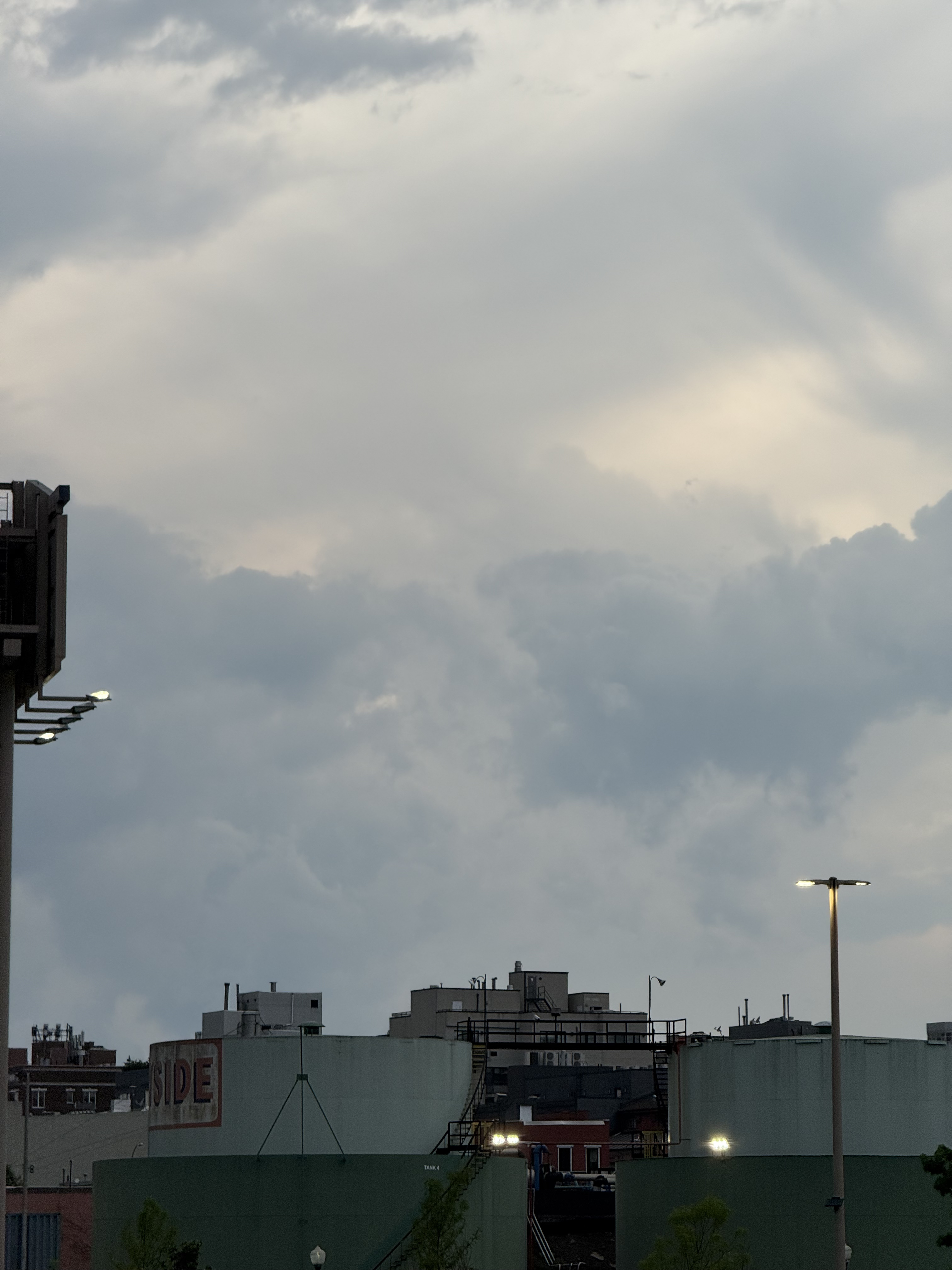 fully clouded sky makes interesting patterns over green fuel tanks with the lights just turning on for the night