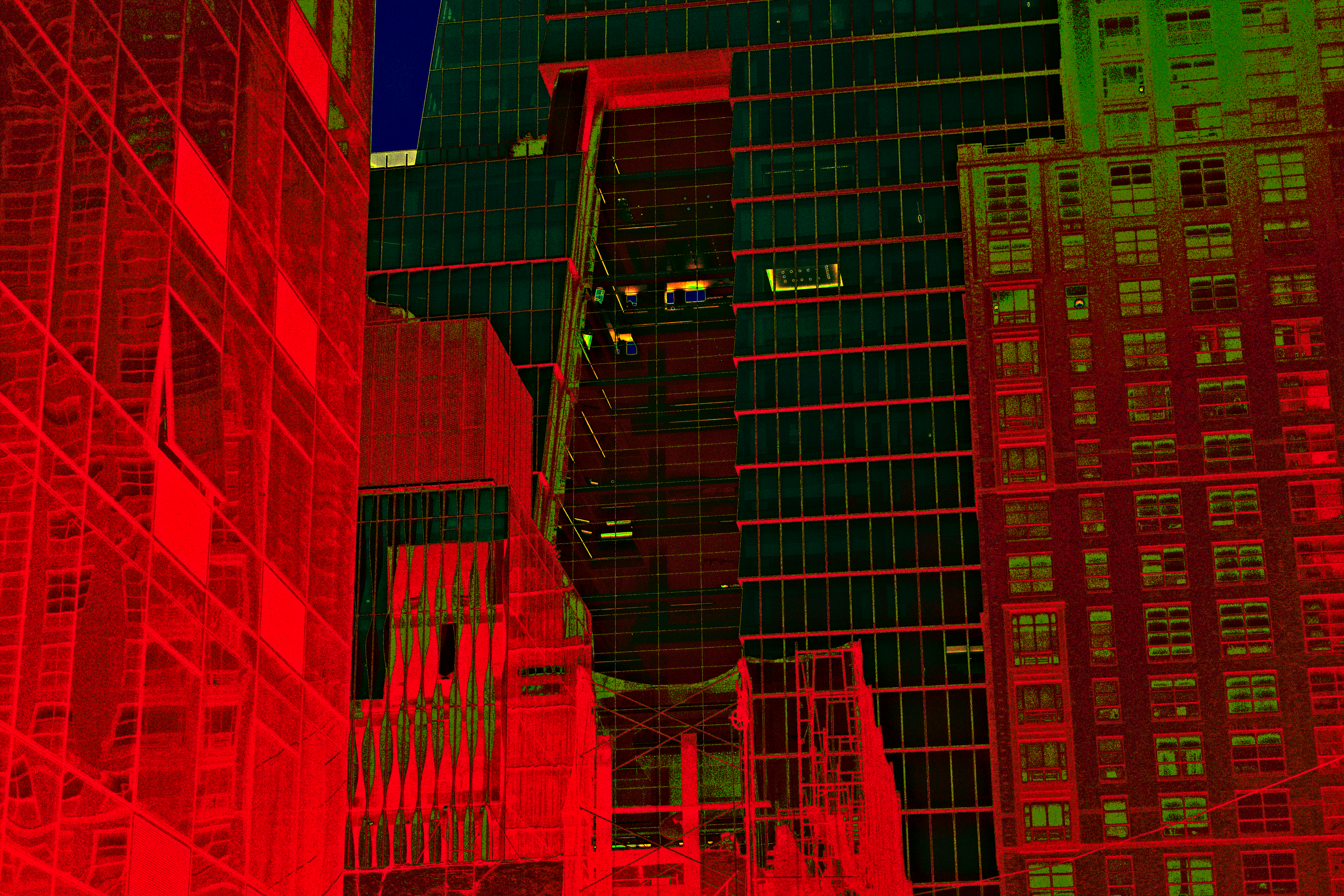 two buildings, colored impossibly pure red, red light leaking out their windows and green tint covering swaths like moss, flank a similarly-red construction site at the foot of a towering green-and-red-lined skyscraper, all its windows nearing pure black. The only lights visible are pure-black ones giving off a yellow halo, with a deep blue sky just barely visible beyond everything.