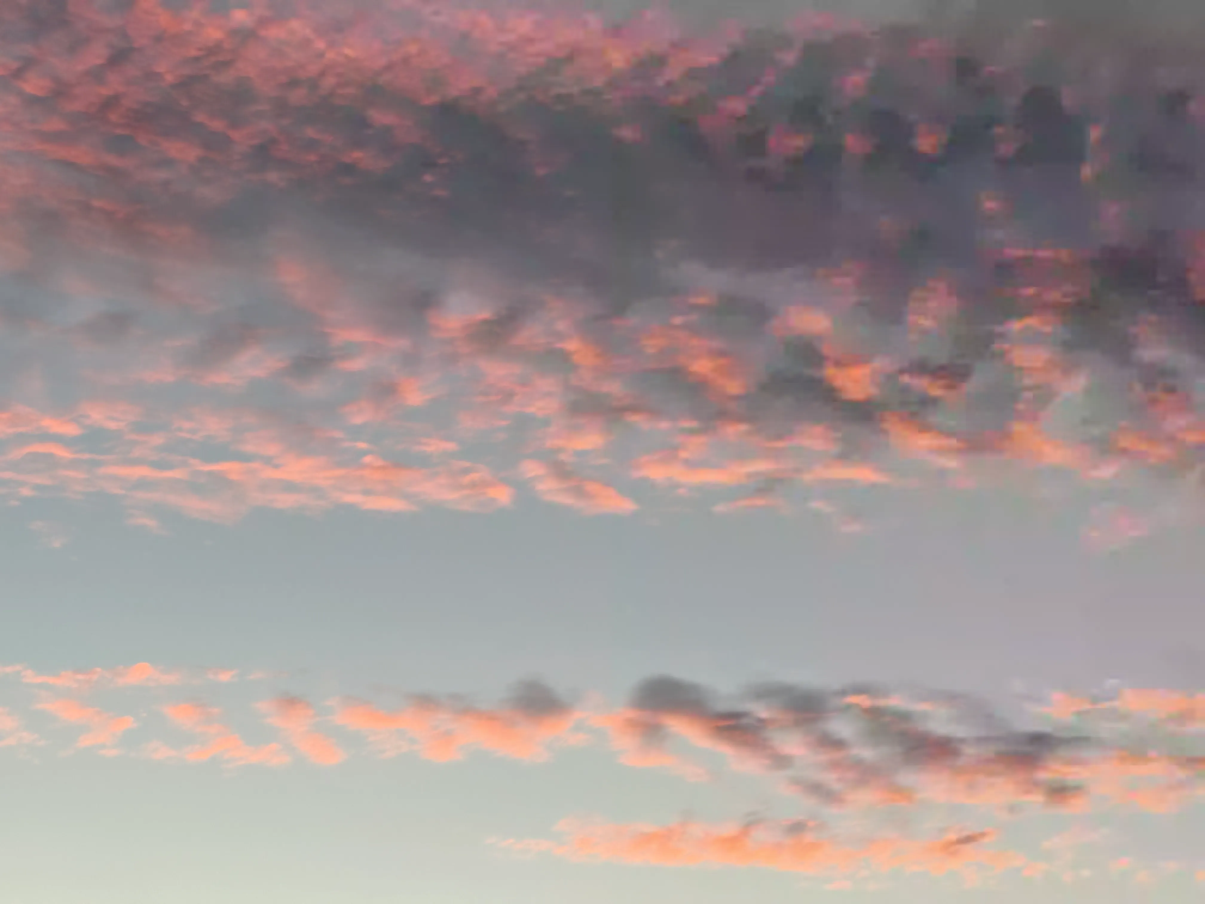 A pink and blue sunset gives way to highly compressed dark gray clouds