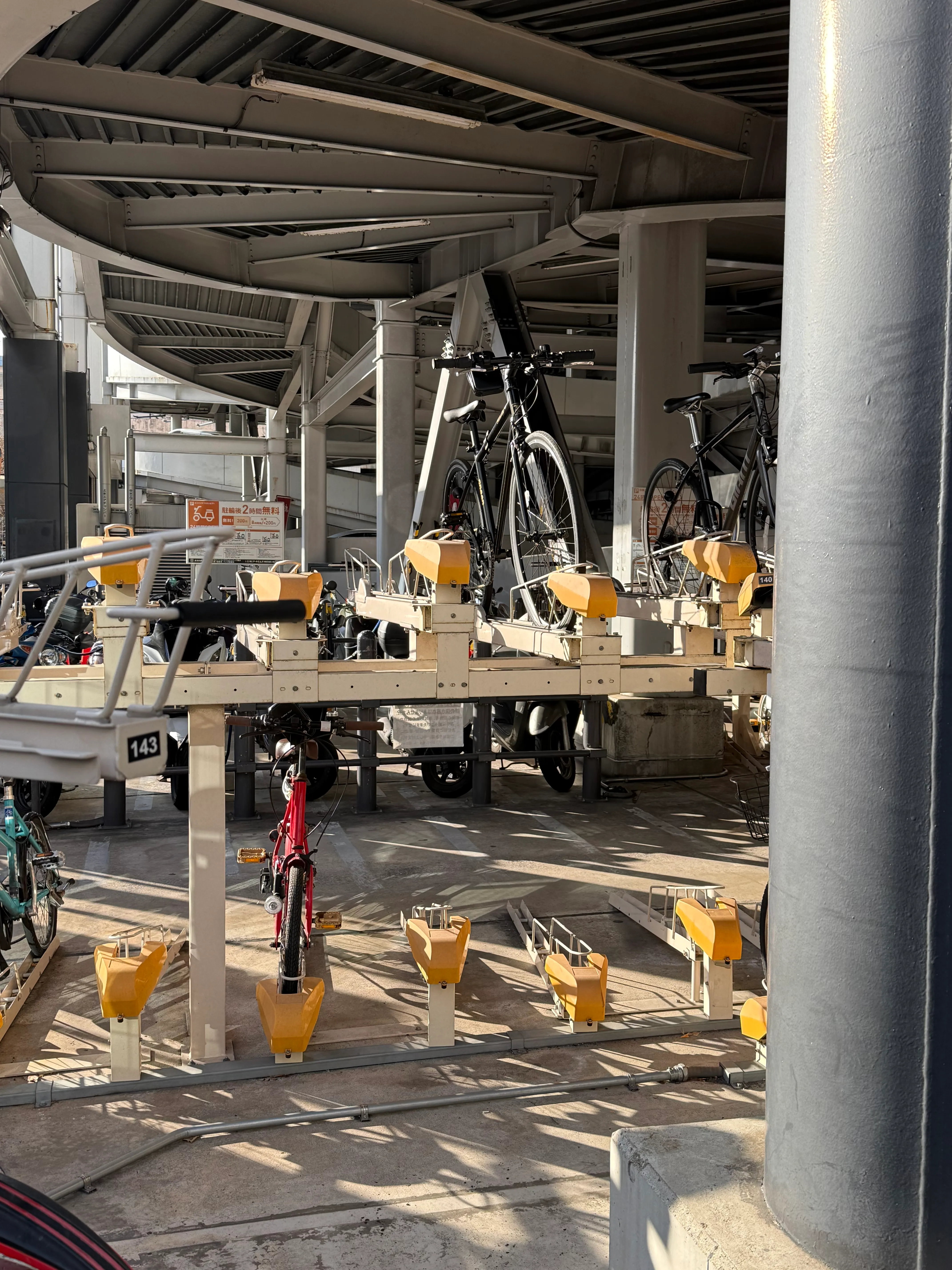 A double-decker bike rack under a pedestrian overpass