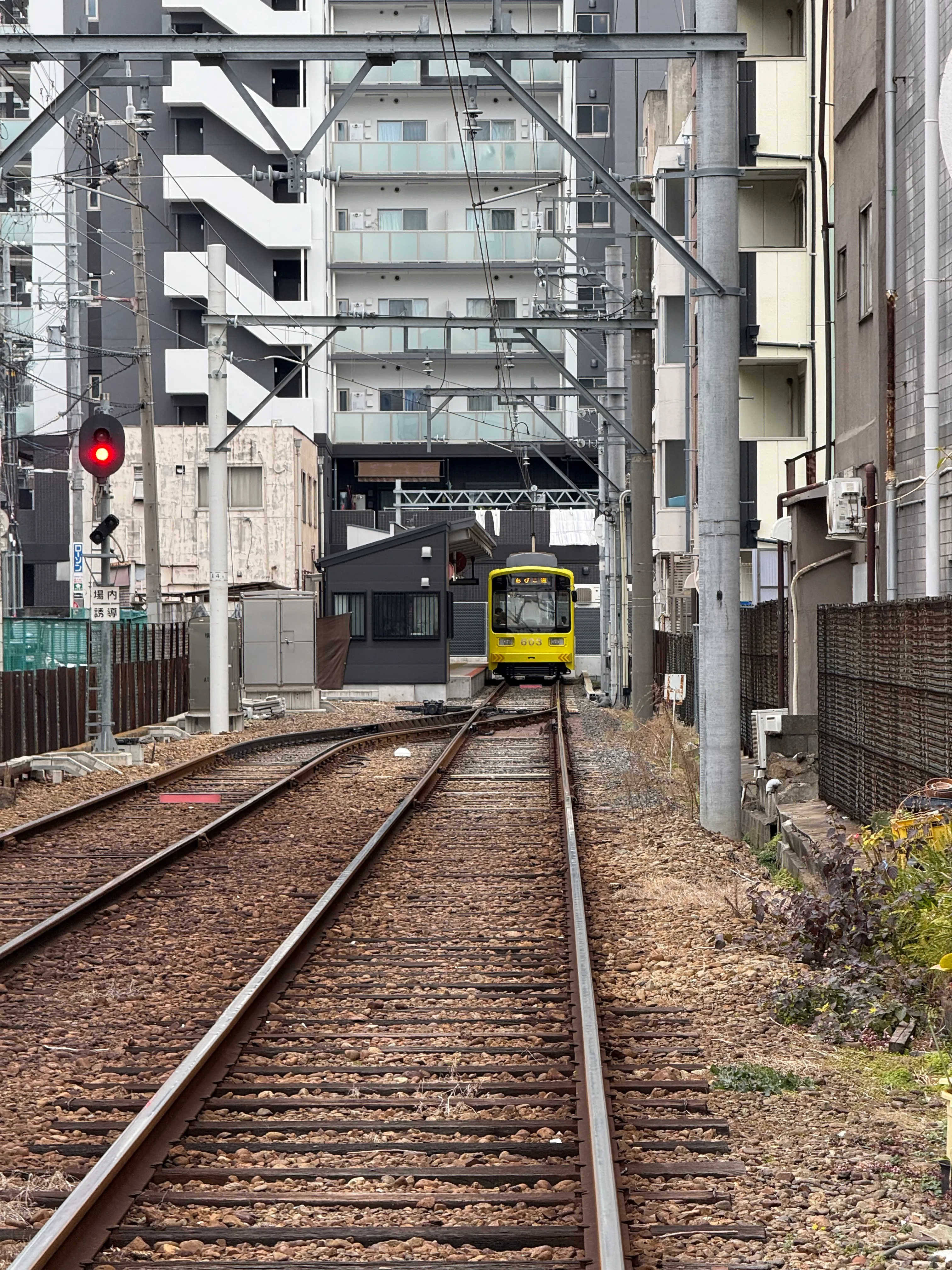 An out-of-service train is nestled between apartment buildings and overhead wires