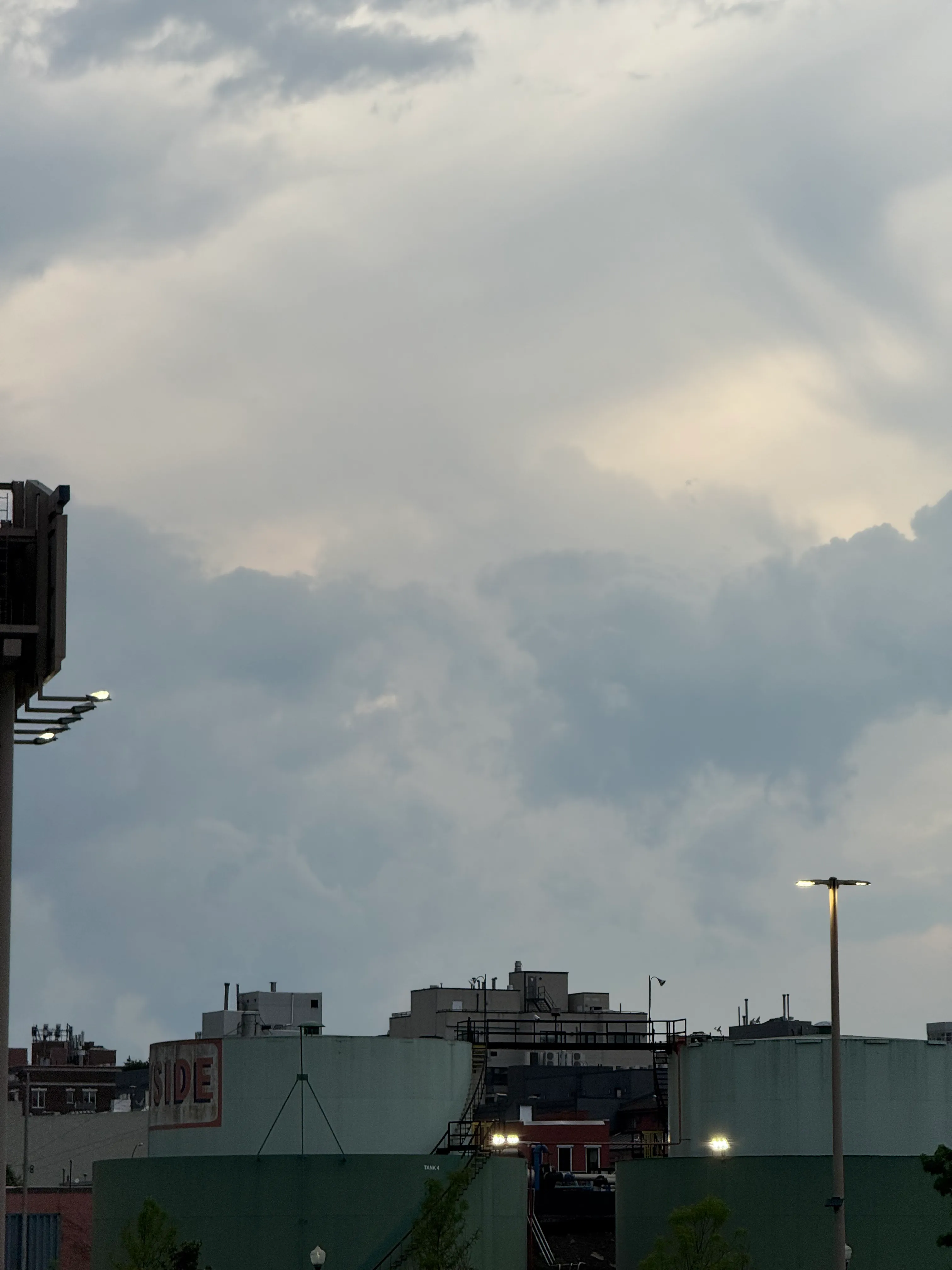 fully clouded sky makes interesting patterns over green fuel tanks with the lights just turning on for the night
