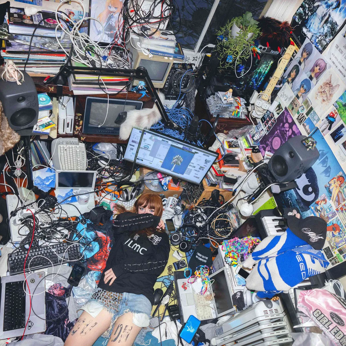 Ninajirachi is surrounded by all sorts of computer equipment &#x26; wires in a chaotically-organized room